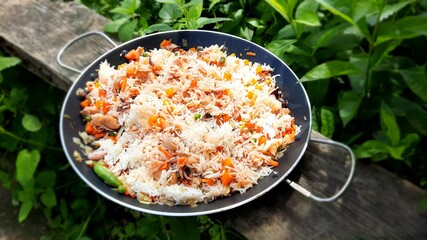 Traditional Spanish seafood paella in a frying pan covered with green leaves.