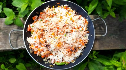 Traditional Spanish seafood paella in a frying pan covered with green leaves.