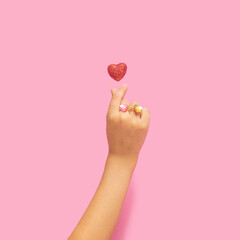 K pop concept. A girl teenager hand with two heart shape rings showing finger heart gesture. Red...