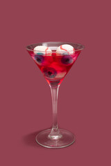 Horror creepy drink concept. Martini glass full with eyeballs red color drink against dark plum background