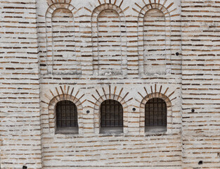 Fototapeta na wymiar Old stone wall with three windows. The beauty of the old building.