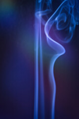 A vertical shot of smoke in colorfull backlight with a blue note