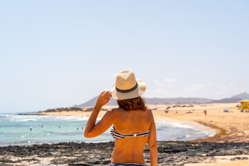 A young tourist with a hat on the beaches of the Corralejo Natural Park, Fuerteventura, Canary Islands. Spain