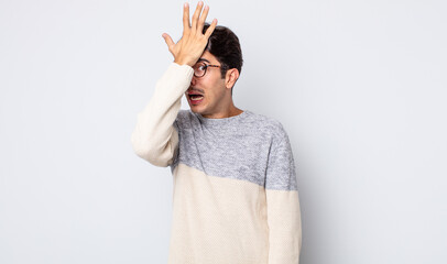 young handsome hispanic man raising palm to forehead thinking oops, after making a stupid mistake...