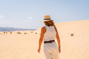 A young tourist wearing a hat walking along the sand on the beaches of the Corralejo Natural Park, Fuerteventura, Canary Islands. Spain