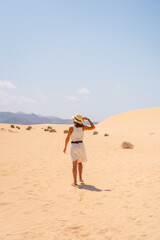 A young tourist wearing a hat walking along the sand on the beaches of the Corralejo Natural Park, Fuerteventura, Canary Islands. Spain