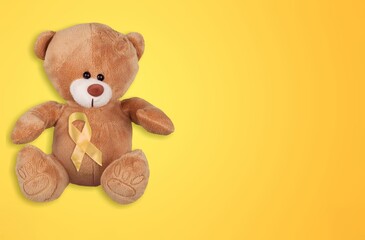 Yellow Ribbon with Bear toy on color background for supporting kid living and illness.