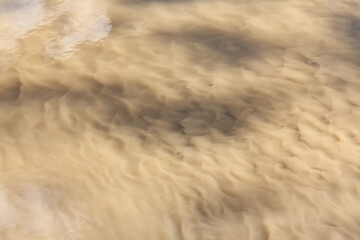 Flowing muddy water background . Ripples on the water surface
