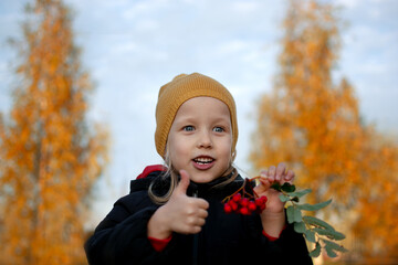 the girl holds a red rowan in her hand, and with the other hand shows like