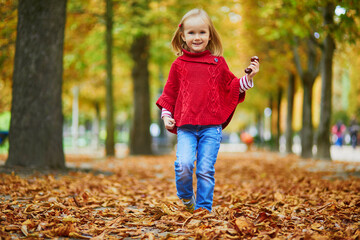 Adorable preschooler girl walking in Tuileries garden in Paris, on a fall day