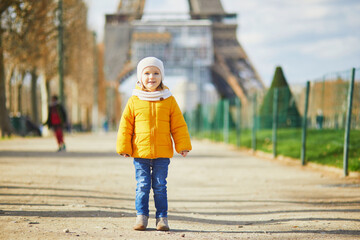 Adorable toddler girl walking near the Eiffel tower in Paris, France