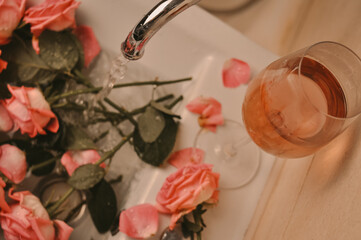 Glass of wine and bouquet of pink roses in sink