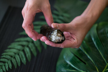 The process of making and decorating tuna Temaki Hand Roll. Hand Cooking Temaki Tuna Sushi in Japanese restaurant. Black background with green plants 
