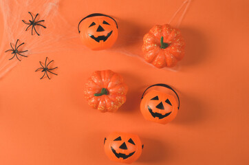 Halloween holiday concept. Pumpkins and spiders on a web on an orange background. Decorations for halloween on an orange background. Halloween party