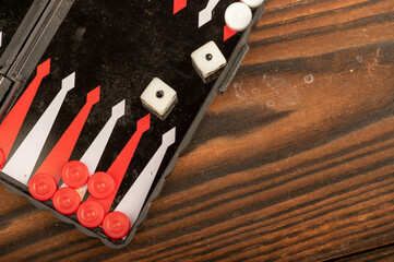 Backgammon board with chips and dice on a wooden table, close-up, selective focus.