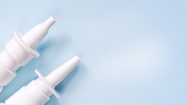 2 white nasal sprays on a light blue background. The concept of autumn diseases, allergies.