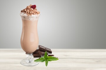 Chocolate milkshake with cream decorated chocolate portions on table.