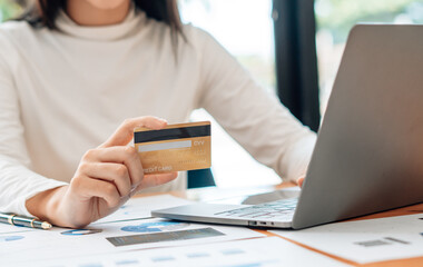 Woman hand holding credit card and using laptop at home, Businessman or entrepreneur working, Online shopping, e-commerce, internet banking, spending money, working from home concept