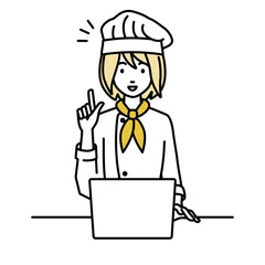 デスクで座ってPCを開いて何かひらめいた調理師の女性