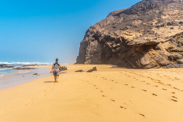 A young father in the Roque del Moro of the Cofete beach of the natural park of Jandia, Barlovento,...
