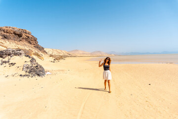 A young tourist walking along the Sotavento beach, ideal for sports such as Kitesurfing or sky...
