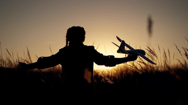 Happy girl with oy in natural park. Child runs on grass with an airplane. Chidhood dream. Happy baby girl with toy airplane at sunset. Child runs on grass in field. Dream travel concept