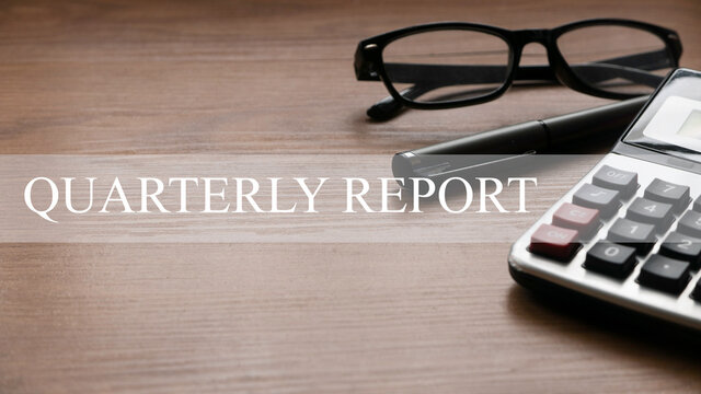 Quarterly report concept with glasses,pen and calculator on wooden background.