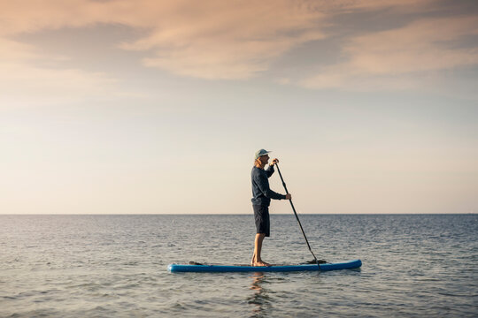 Male instructor paddleboarding in sea during summer vacation