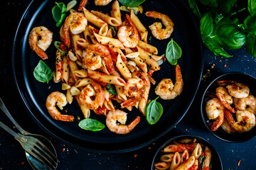 Penne with fried prawns in on black wooden background
