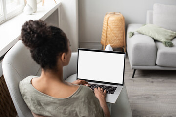 Young woman using laptop computer at home. Blank empty white screen mock up. Freelance, student lifestyle, education, web conference, video call, technology and online shopping concept