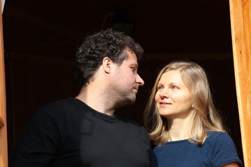 Portrait of a happy couple looking at each other isolated on black close-up. Young people in love with a sensual look stand at the door of the house in the sunlight