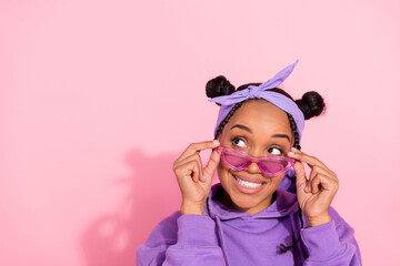 Photo of pretty attractive afro woman wear purple hoodie buns arms eyeglasses looking empty space smiling isolated pink color background