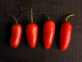 Four freshly harvested homegrown hot peppers on a rustic kitchen table