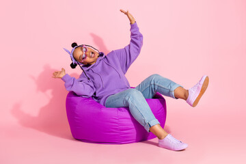 Photo of funny funky afro woman wear purple hoodie buns sitting beanbag fooling smiling isolated...