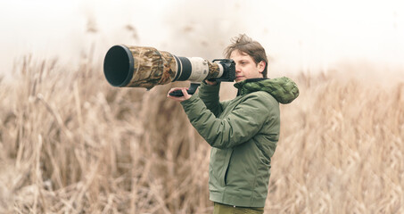 Nature photographer who is looking at the beauty in birds and other animals through binoculars. Explorer looks through binoculars to see things faraway. Nature walk scene while using his binocular
