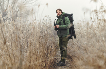 Wildlife photographer using telephoto lens with camouflage coating photographing wild life using gimbal head on tripod. professional photography equipment for cinematic shooting in the nature outdoor