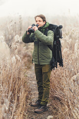 Nature photographer who is looking at the beauty in birds and other animals through binoculars. Explorer looks through binoculars for biodiversity ecosystem. Nature walk scene while using binoculars