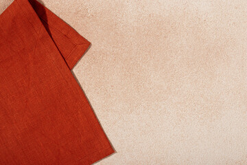 Textile orange serving napkin on beige plastered background