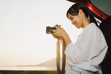 Asian women photographers are using cameras to travel near riverside at the mountain. Evening time with sunny tone. Travel and backpack