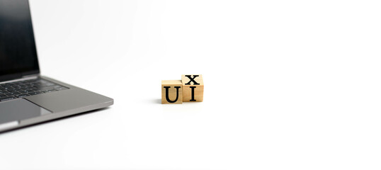 Wooden cube on a white table with text UX, UI. Concept of development and design and development,...