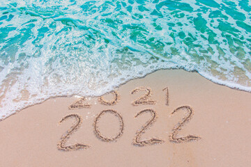 Message Year 2021 replaced by 2022 written on beach sand background. Good bye 2021 hello to 2022 happy New Year coming concept