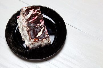 Plate with slice of tasty chocolate cake on table. Yummy dessert on on wooden background, closeup