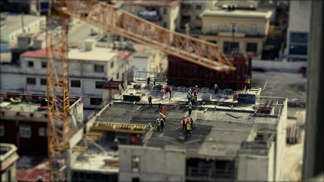 Construction workers wearing high visual clothing and laying steel reinforcement preparing for the concrete to be poured. Tilt and shift, stop motion, miniature world.