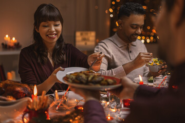 holidays, party and celebration concept - multiethnic group of happy friends having christmas dinner at home
