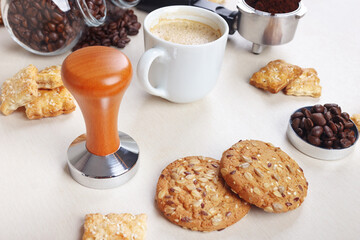 Still life with sweets, cup of coffee, coffee beans and ground coffee on table.