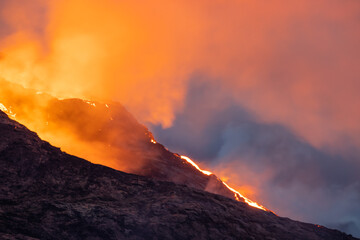Night volcanic eruption. Fresh hot lava, flames and poisonous gases going out from the crater.