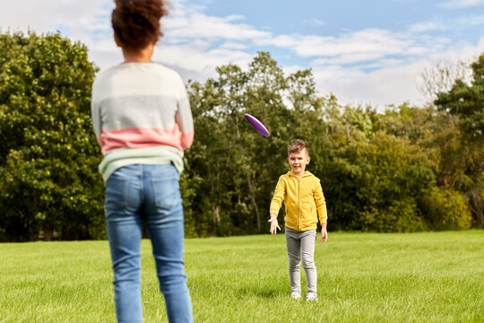 childhood, leisure and people concept - happy children playing game with flying disc at park