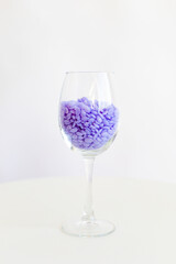 capsules of purple wax for depilation in a transparent glass, on a white background