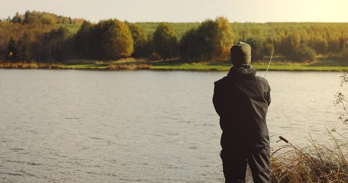 fisherman cast a spinning rod with lure in the lake at sunset. shore fishing