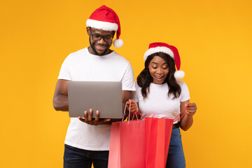 Black Couple Shopping Using Laptop During Christmas Sale, Yellow Background